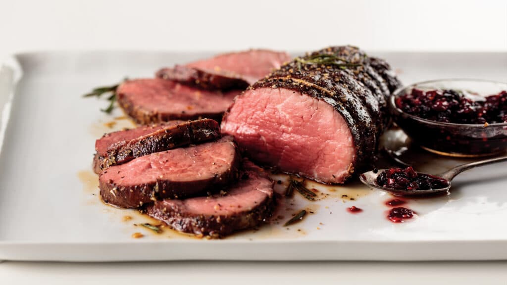 Cooked chateaubriand filet mignon roast with 5 medium-rare sliced pieces. Served with side cranberry sauce.