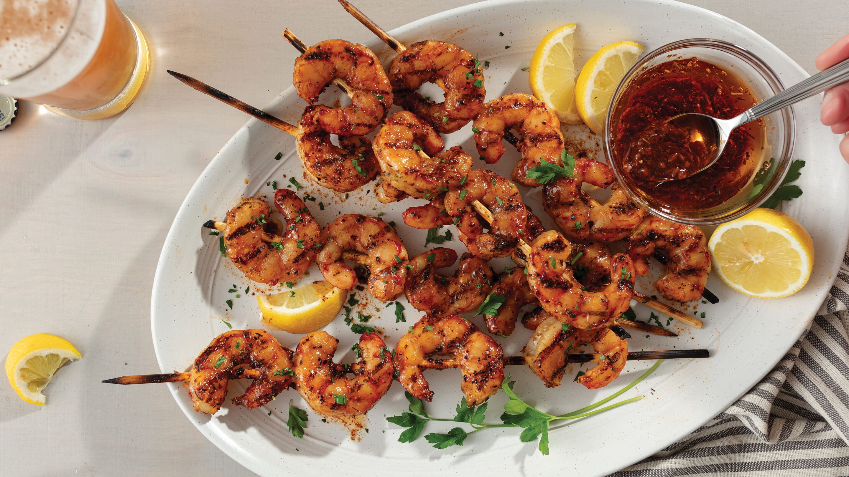 Grilled shrimp on skewers plated with cocktail sauce and lemon wedges