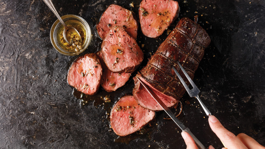 Chateaubriand cooked to medium rare sliced on a cutting board