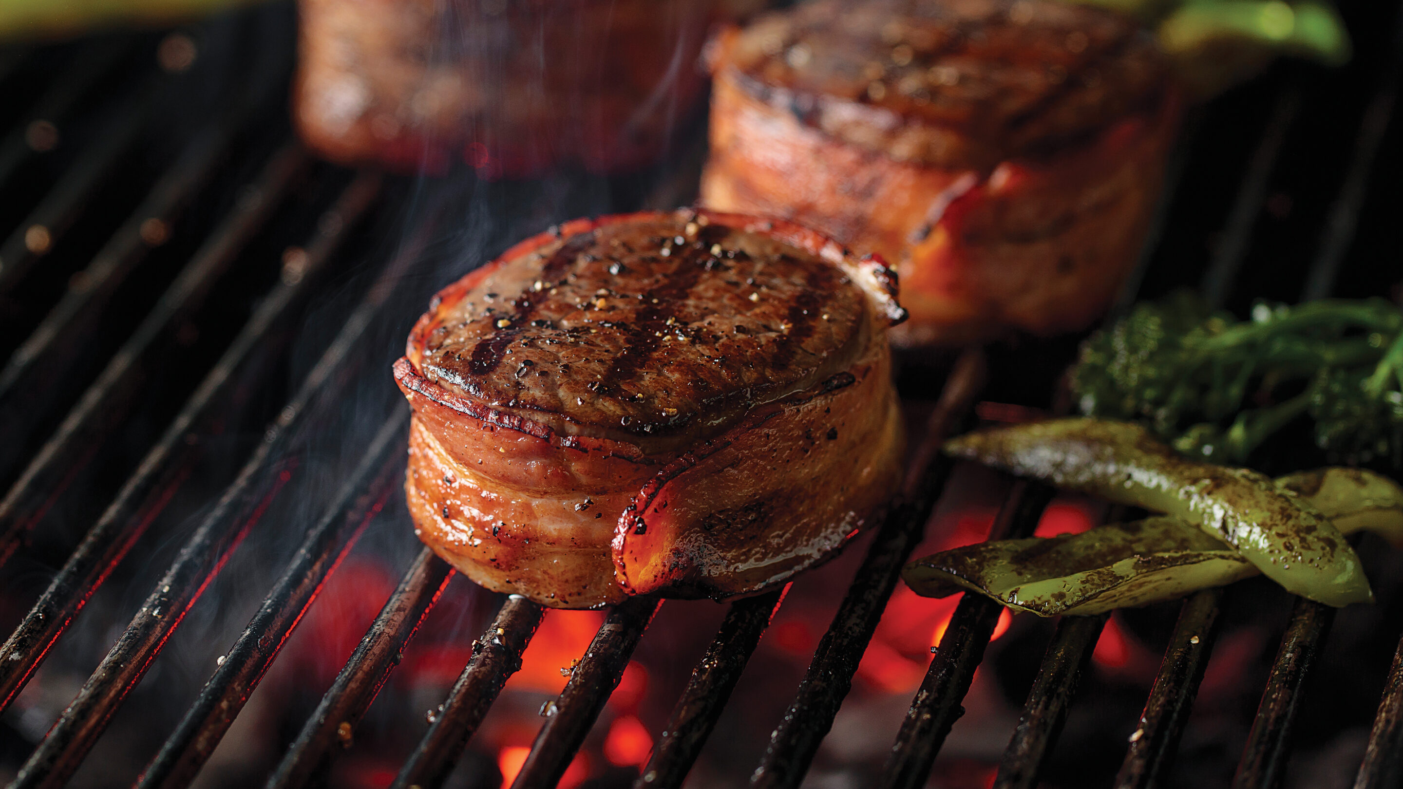 Chef holding white plate with cooked, sliced filet mignon served with a side of broccolini.