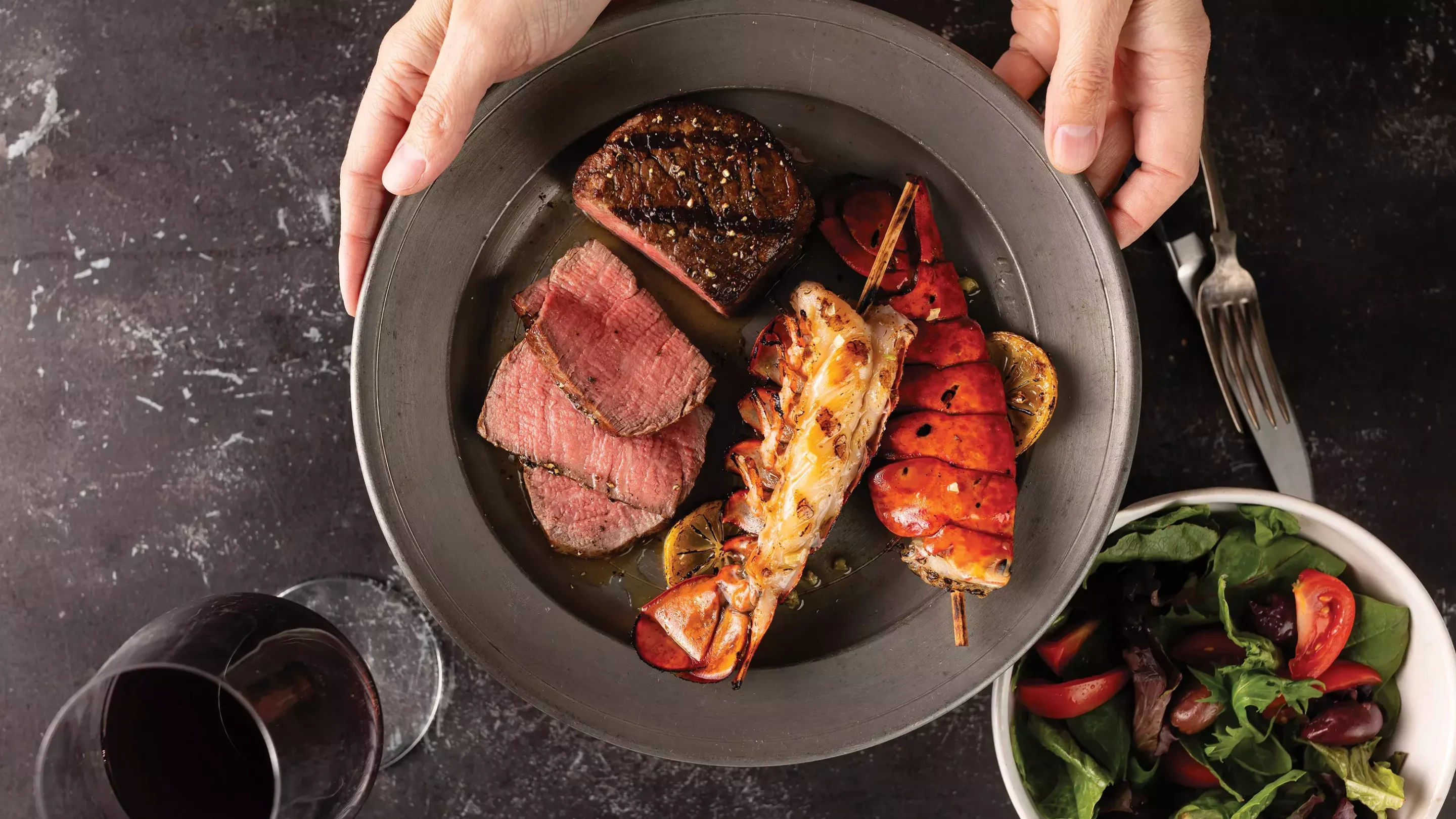 Seared King Cut New York strip steak in cast iron skillet with butter and garlic cloves on a gas stove.