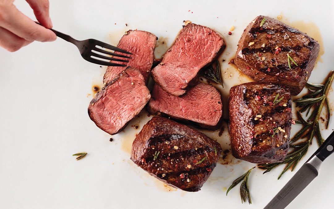 3 grilled top sirloins with beautiful grill marks. 4 slices of rare top sirloin with fork in one slice.