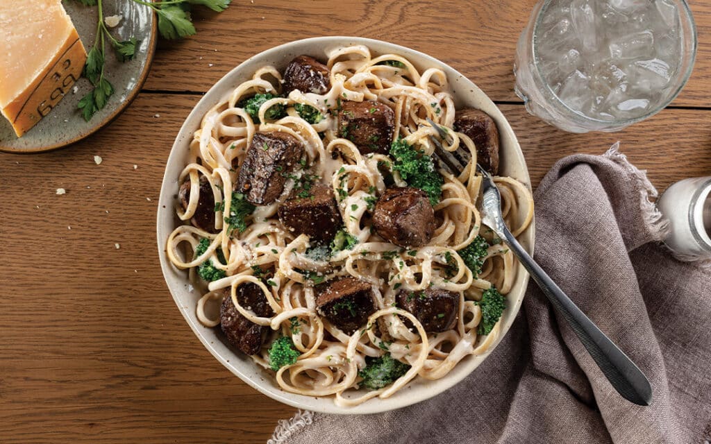 Cheesy pasta with filet mignon tips in a bowl.