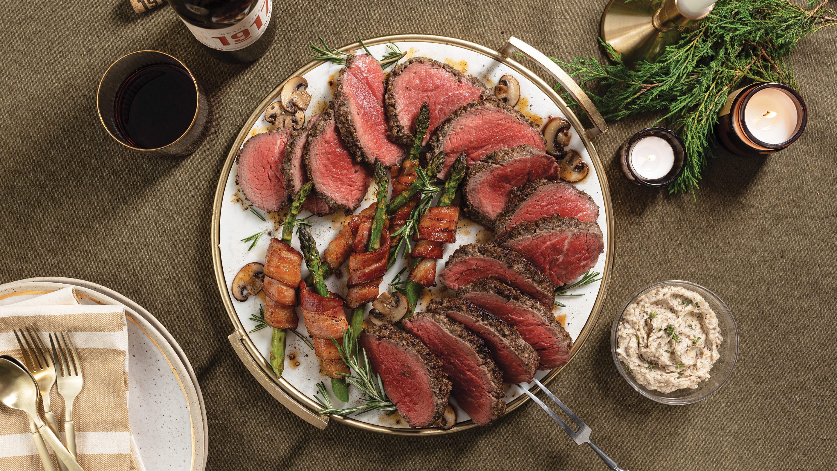 Duxelles-roasted chateaubriand cooked medium-rare, sliced and fanned out on plate with bacon-wrapped asparagus.